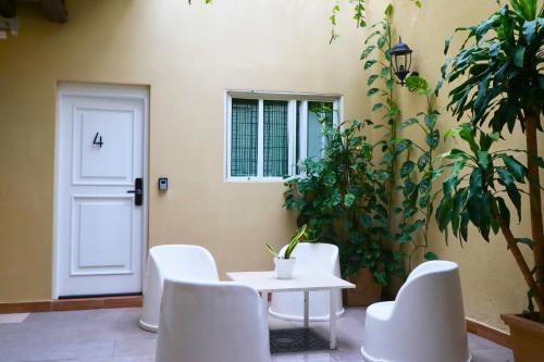 une table et des chaises blanches devant une porte dans l'établissement Heritage Residences Santo Domingo, à Saint-Domingue