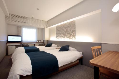 1 dormitorio con 2 camas, mesa y escritorio en Hotel Plaza Osaka, en Osaka