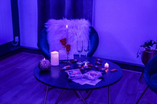 Cette chambre violette comprend une table avec des bougies et des verres à vin. dans l'établissement L'Atelier de rêves, à Metz