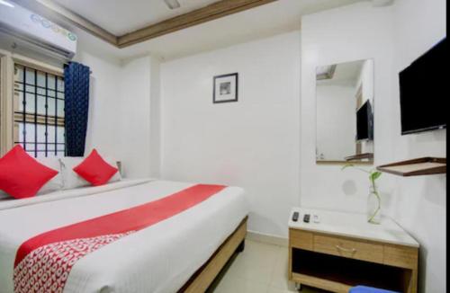 1 dormitorio con 1 cama con almohadas rojas y TV en i5 HOTEL, en Chennai