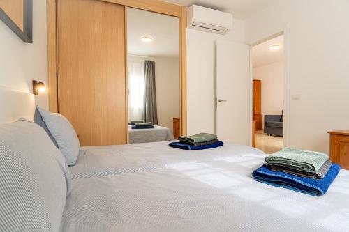 um quarto com uma cama branca e toalhas em Las Casitas de Corralejo em Corralejo