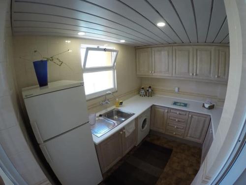 a kitchen with a white refrigerator and a window at T1 Vista Marina de Vilamoura in Vilamoura