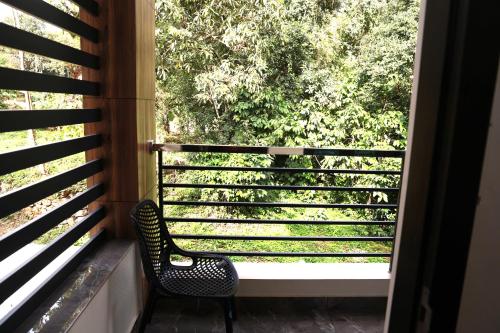 a chair sitting on a balcony looking out a window at ECOSTAY inn in Sultan Bathery