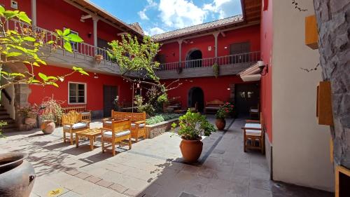 une cour d'un bâtiment rouge avec des tables et des chaises dans l'établissement Tambo del Arriero Hotel Boutique, à Cusco