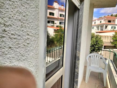 een witte stoel op een balkon met een raam bij Casa Xantarim in Santarém