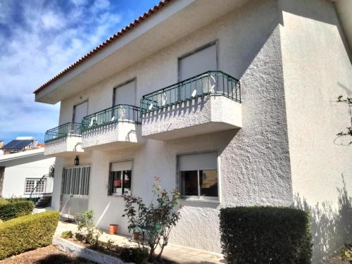 een wit gebouw met een balkon en struiken bij Casa Xantarim in Santarém