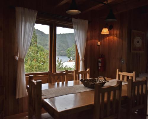 uma sala de jantar com uma mesa e uma grande janela em Apart Hotel Orilla Mansa by Visionnaire em San Martín de los Andes