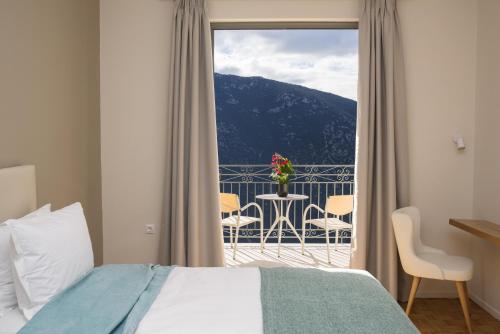 1 dormitorio con 1 cama y balcón con mesa y sillas en V Hotel Delphi, en Delfos