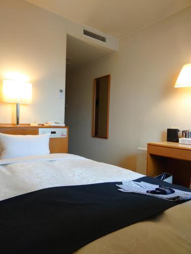 una camera con letto e scrivania con lampada di Aomori Green Park Hotel Annex ad Aomori