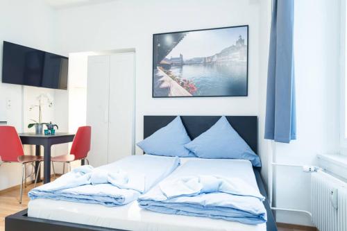 a bedroom with a bed with blue pillows and a table at HITrental Old Town Apartments in Luzern