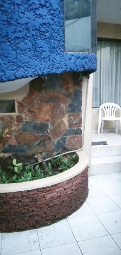 un mur en pierre avec une chaise à côté d'un bâtiment dans l'établissement El descanso céntrico, à Santa Cruz de la Sierra