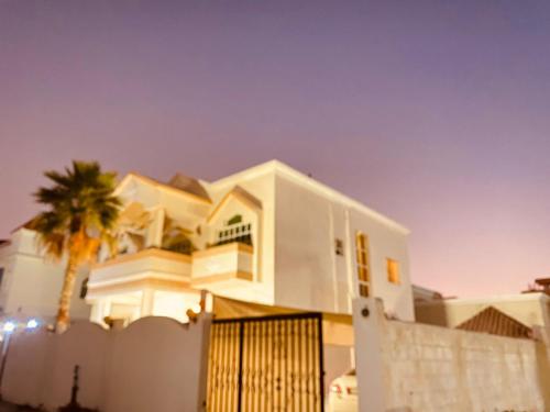 uma casa branca com uma palmeira em frente em Holiday Home Rent villa em Sharjah