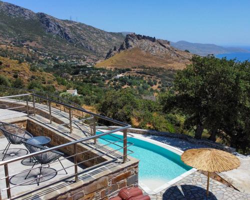 - une piscine avec des chaises et un parasol dans l'établissement Drys Villas Mekoynida, à Karistos