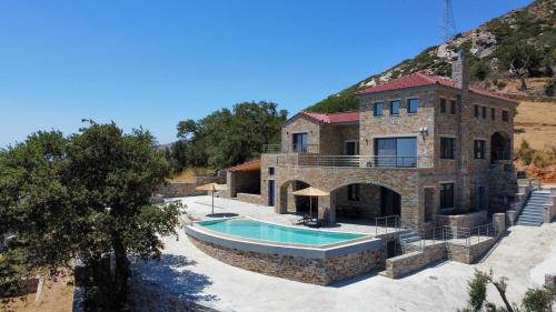 une grande maison en pierre avec une piscine dans l'établissement Drys Villas Mekoynida, à Karistos