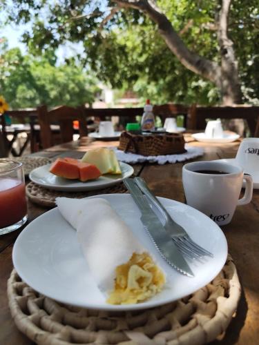 a table with plates of food and a fork and a cup at Pousada Cafe e Mar Jeri in Jericoacoara