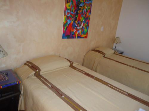 two beds in a room with a painting on the wall at Casa Elena in Antigua Guatemala