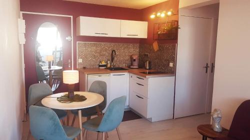 una cucina con tavolo, sedie blu e tavolo di La Perle Marine, Cosy et rénové, 200 m de la plage, 1 chambre, parking et Wifi a Sète