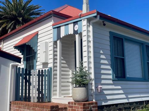 une maison blanche avec une clôture et une plante dans l'établissement Cosy coastal cottage- Allwood Harbour, à Kiama