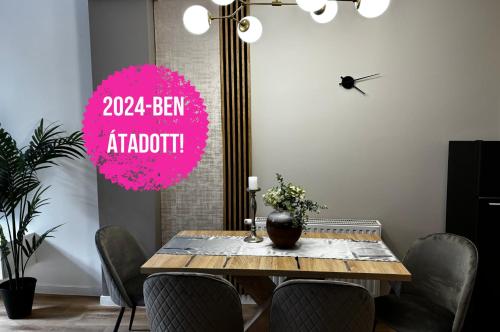 a dining room with a table with chairs and a clock at Z8 Prémium Apartman in Kaposvár