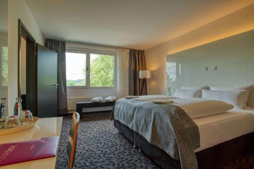 Cama ou camas em um quarto em FourSide Plaza Hotel Trier, Trademark Collection by Wyndham