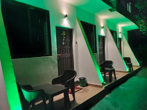 a green room with chairs and tables and a door at Beach Deluxe Carolina GuestHouse & VIlla in Colva