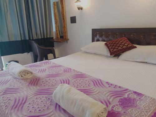 a bedroom with a bed with a purple and white bedspread at Beach Deluxe Carolina GuestHouse & VIlla in Colva