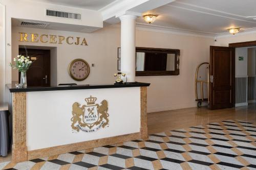 a hotel lobby with a reception counter and a clock at Royal Hotel Modlin in Nowy Dwór Mazowiecki