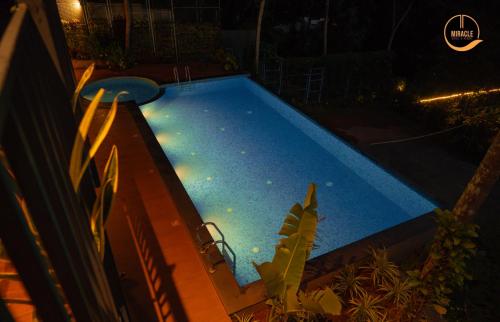 ein Schwimmbad mit Lichtern in einem Hinterhof in der Nacht in der Unterkunft Miracle Hotel and Resorts in Kozhikode