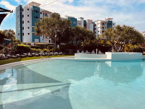 a large swimming pool with chairs and buildings in the background at Atlantis Marcoola in Marcoola