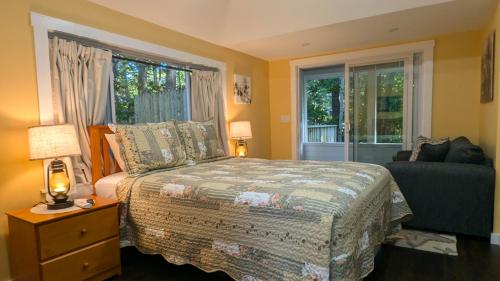 ein Schlafzimmer mit einem Bett, einem Fenster und einem Sofa in der Unterkunft Hinckleys Dreamwood Cottages in Bar Harbor