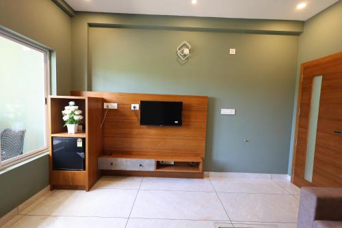 a living room with a flat screen tv on a wall at Riders Den in Mananthavady