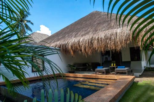 une villa avec une piscine et un toit de paille dans l'établissement Atmosphere Resorts & Spa, à Dauin