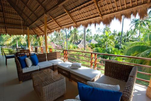 une terrasse couverte avec une table et des chaises ainsi qu'un balcon arboré dans l'établissement Atmosphere Resorts & Spa, à Dauin