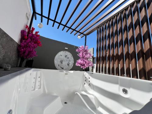 Departamento Inteligente con Jacuzzi Privado en Zapopan في غواذالاخارا: حوض استحمام أبيض في غرفة بها زهور أرجوانية