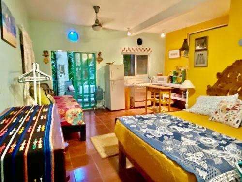 a bedroom with two beds and a kitchen with yellow walls at Casa Cereza Apartments in Puerto Vallarta