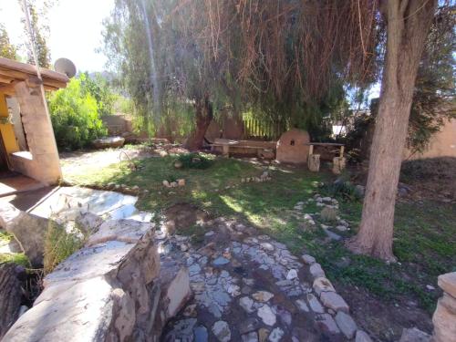 un jardín con una pared de piedra y un árbol en La Pirquita, en Tilcara