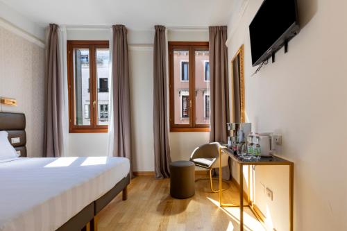 a hotel room with a bed and a tv at Numa Venice Palazzo Orseolo in Venice