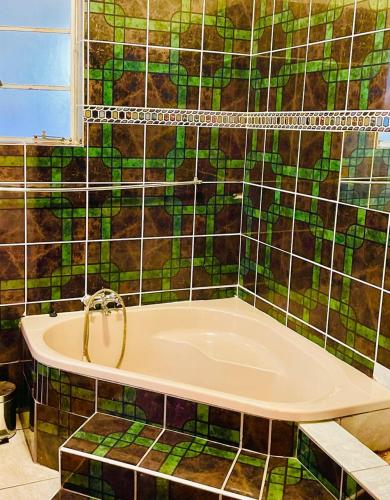 a bath tub in a bathroom with a tiled wall at GoldenWays Motel 2 in Mbabane