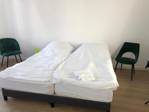 un letto bianco con due sedie in una stanza di Digitaler Nomade a Zittau