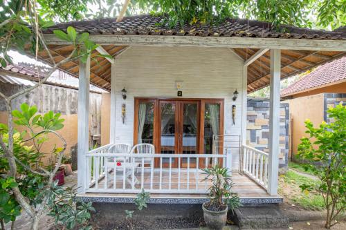 Casa blanca con porche con mesa y sillas en Blue Lagoon Secret Villas, en Nusa Lembongan