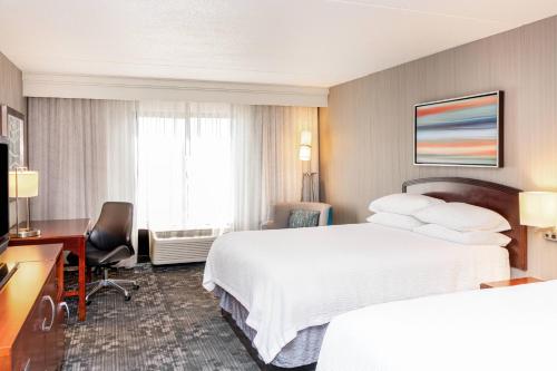 ブルーミントンにあるCourtyard by Marriott Bloomingtonのベッド2台とデスクが備わるホテルルームです。