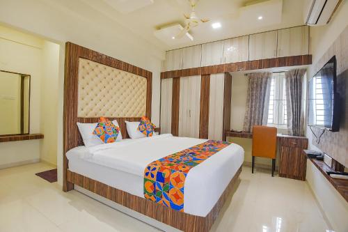 a bedroom with a large bed and a desk at FabHotel Darshan Adobe - Nr Bus stand in Coimbatore