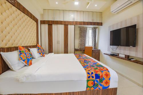 a bedroom with a large bed and a flat screen tv at FabHotel Darshan Adobe - Nr Bus stand in Coimbatore