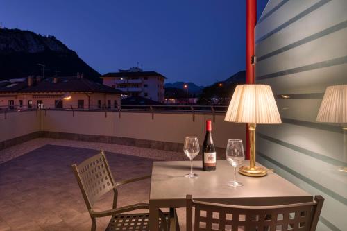 een tafel met twee wijnglazen en een lamp op een balkon bij Hotel Sporting Trento in Trento