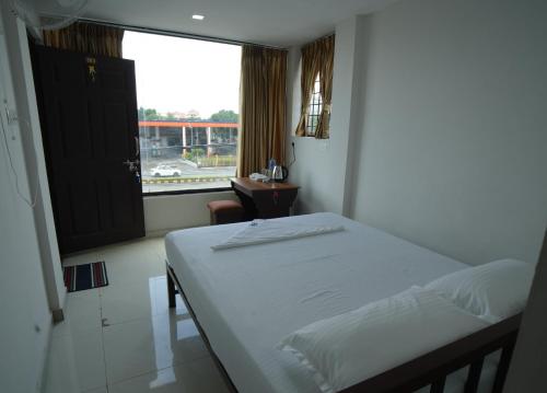 ein kleines Schlafzimmer mit einem Bett und einem Fenster in der Unterkunft Port View Residency PVR in Nedumbassery