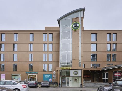 un gran edificio con coches estacionados en un estacionamiento en B&B HOTEL Vejle, en Vejle