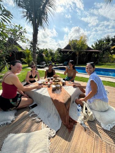 un grupo de mujeres sentadas en una mesa cerca de una piscina en Nunu Bali Eco Friendly Retreat, en Canggu