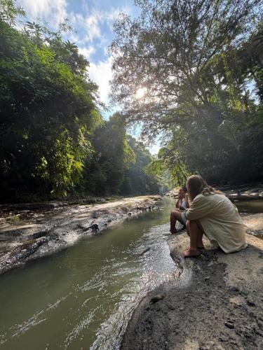 dos personas sentadas en una roca junto a un río en Nunu Bali Eco Friendly Retreat, en Canggu