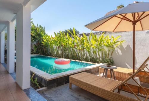 een zwembad met een stoel en een parasol bij Braban Sari Bali in Seminyak