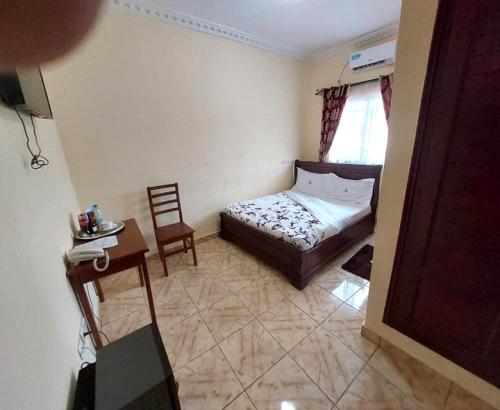 1 dormitorio con 1 cama, 1 mesa y 1 silla en DF HOTEL plazza, en Yaoundé